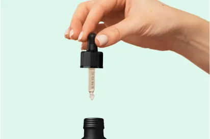 Mão de um médicMão segurando a tampa de um frasco de óleo CBDo dando um comprimido na mão de um paciente